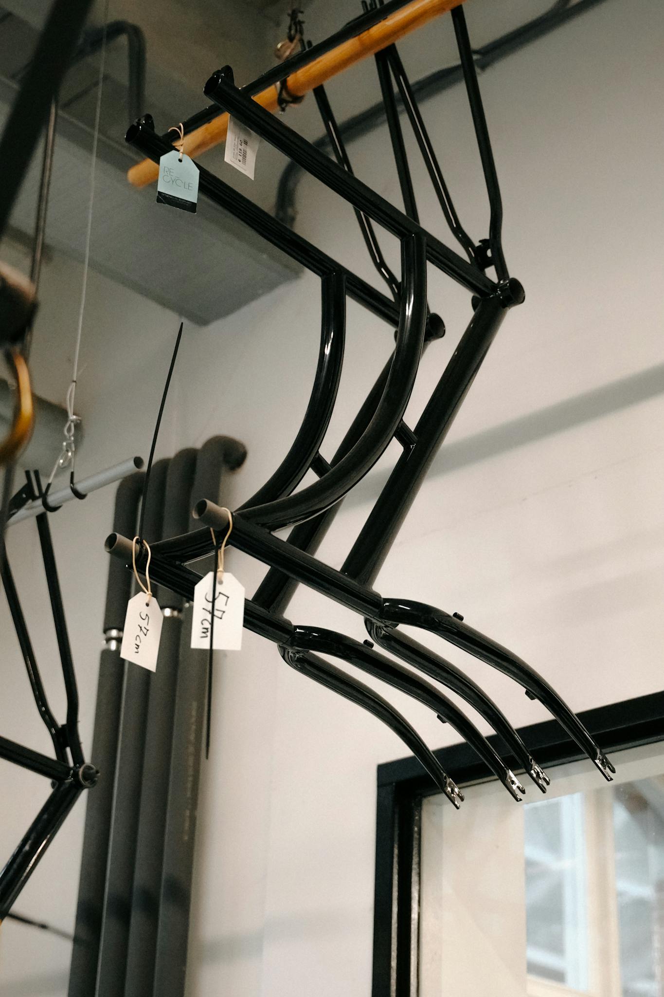Hanging black steel bicycle frames in an Amsterdam workshop with natural lighting.